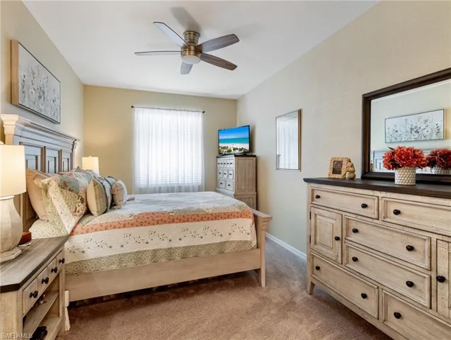 Bedroom with light carpet, baseboards, and a ceiling fan