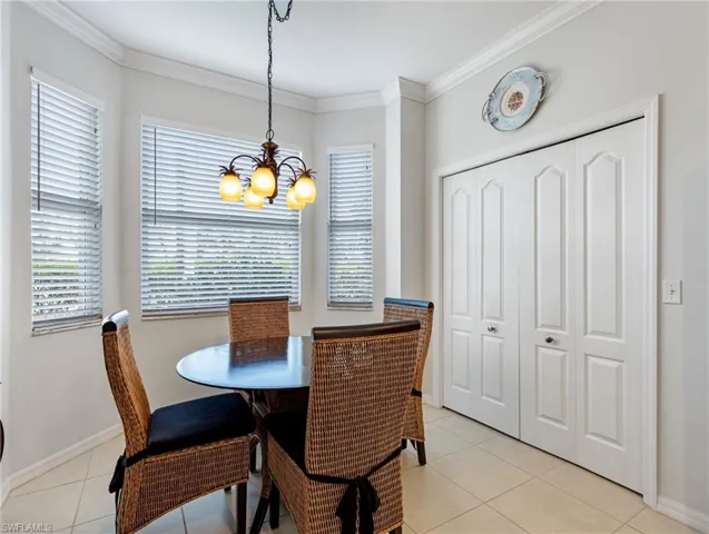 Dining space with an inviting chandelier, baseboards, ornamental molding, and light tile patterned floors