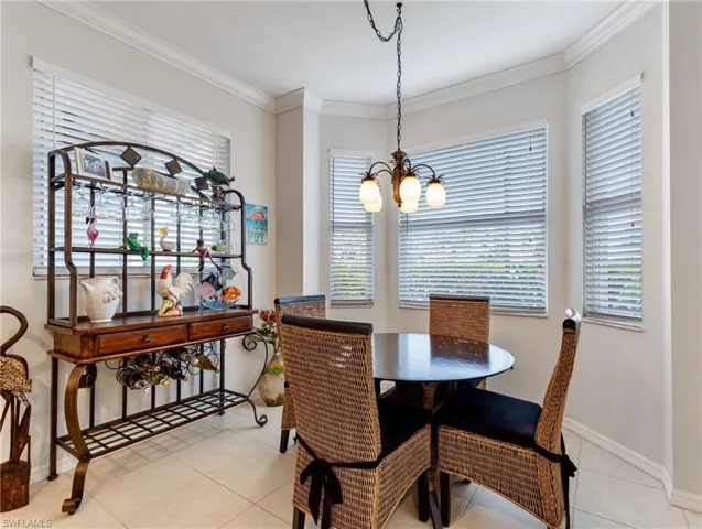 Dining area with light tile patterned floors, a notable chandelier, baseboards, and crown molding