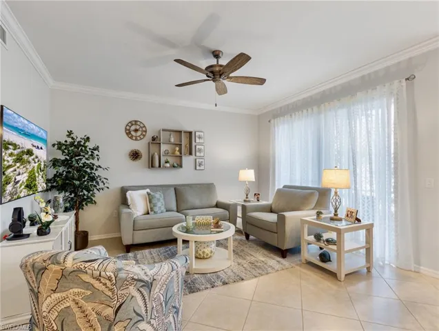 Living area with visible vents, baseboards, a ceiling fan, crown molding, and light tile patterned flooring