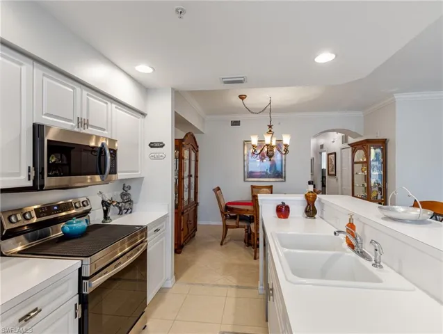 Kitchen featuring a sink, ornamental molding, appliances with stainless steel finishes, and arched walkways