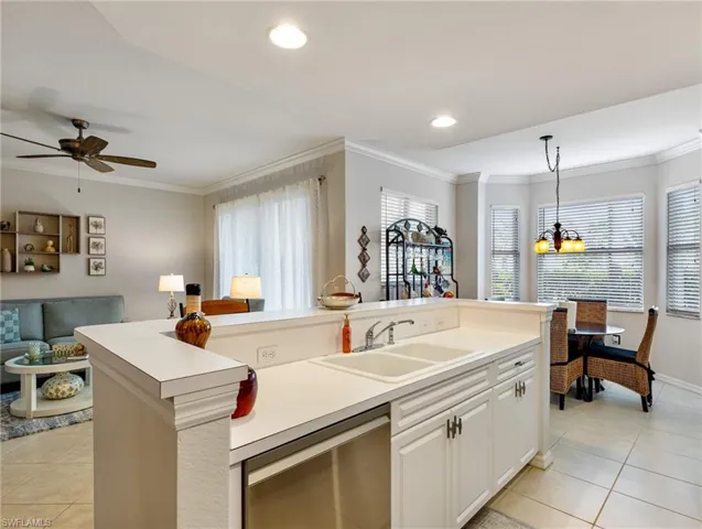 Kitchen featuring ornamental molding, open floor plan, light tile patterned flooring, dishwasher, and a sink