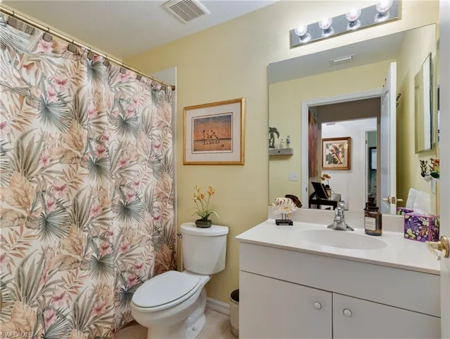 Full bath featuring tile patterned floors, vanity, visible vents, and toilet