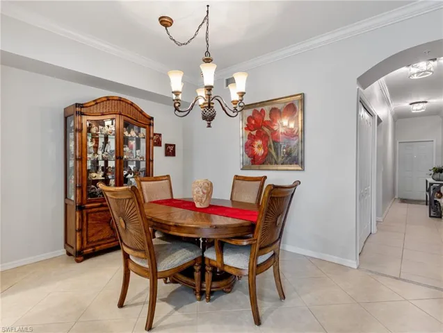 Dining space with crown molding, arched walkways, and light tile patterned flooring