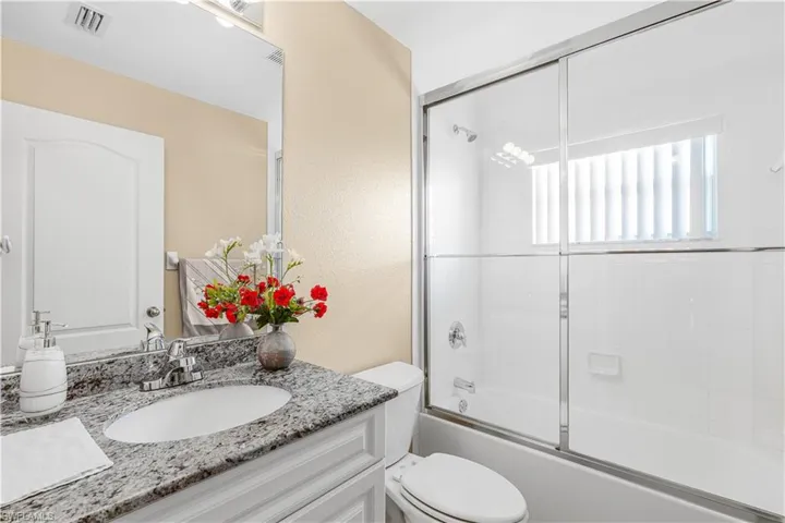 Bathroom featuring vanity, visible vents, toilet, and enclosed tub / shower combo