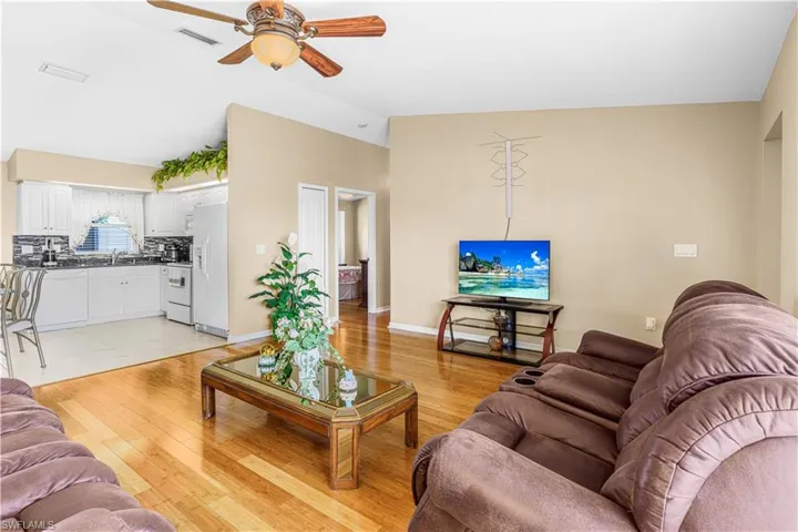 Living area featuring light wood-type flooring, lofted ceiling, a ceiling fan, and visible vents