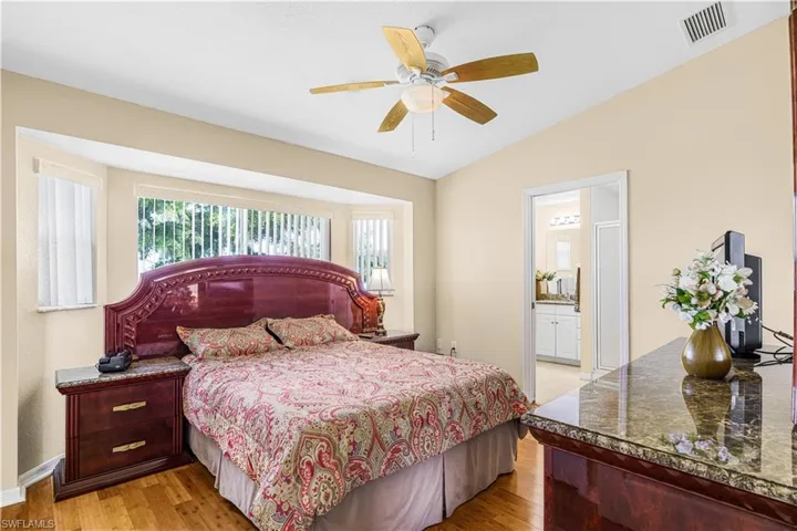 Bedroom featuring visible vents, light wood-style flooring, vaulted ceiling, and baseboards