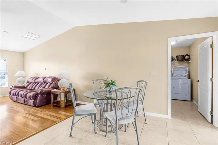 Dining space with washer / clothes dryer, light tile patterned floors, baseboards, and lofted ceiling