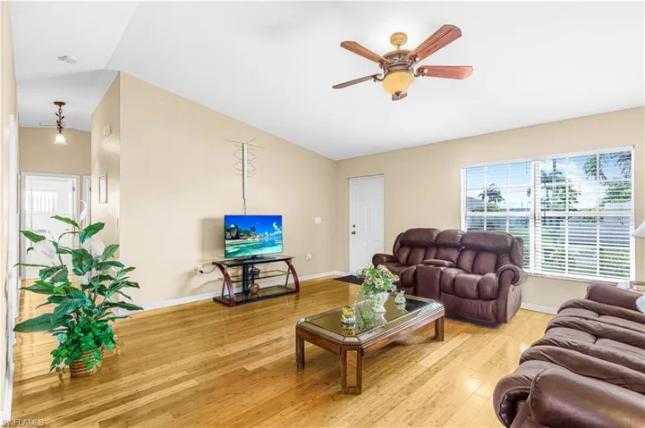 Living room with baseboards, a ceiling fan, vaulted ceiling, and wood finished floors