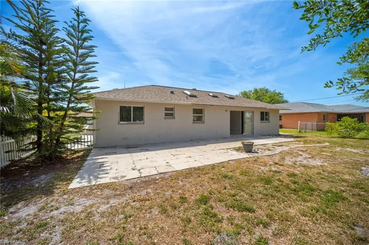 Back of house with stucco siding, roof with shingles, a patio, and fence