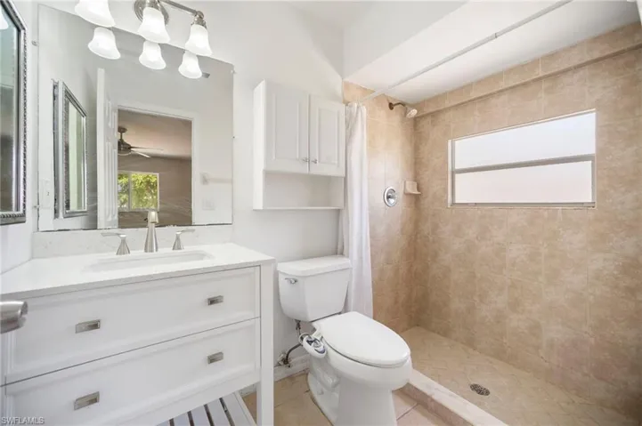 Bathroom with tile patterned floors, toilet, vanity, and a tile shower
