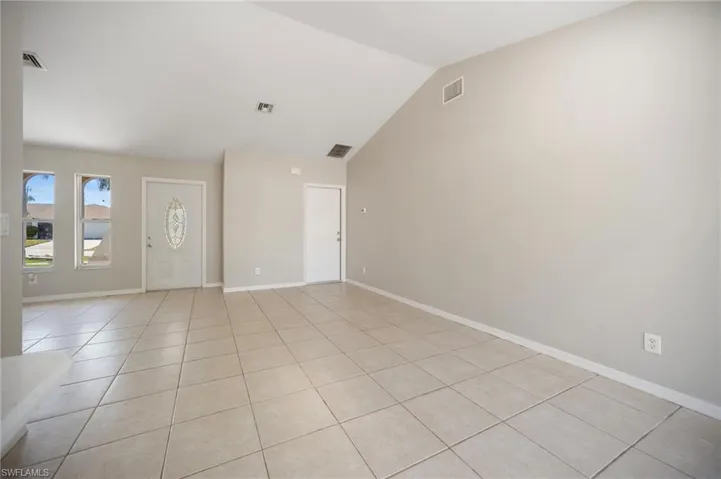 Entry featuring light tile patterned floors, visible vents, baseboards, and vaulted ceiling