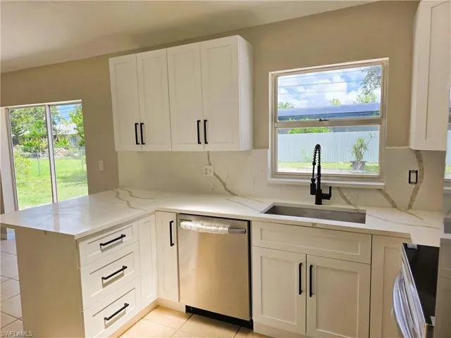 Kitchen with stainless steel appliances, light stone countertops, a peninsula, and decorative backsplash