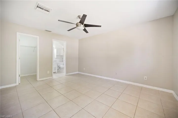 Primary bedroom featuring visible vents, a walk in closet, a closet, baseboards, and ceiling fan