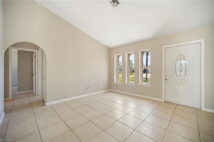 Dining view, baseboards, light tile patterned floors, arched walkways, and high vaulted ceiling