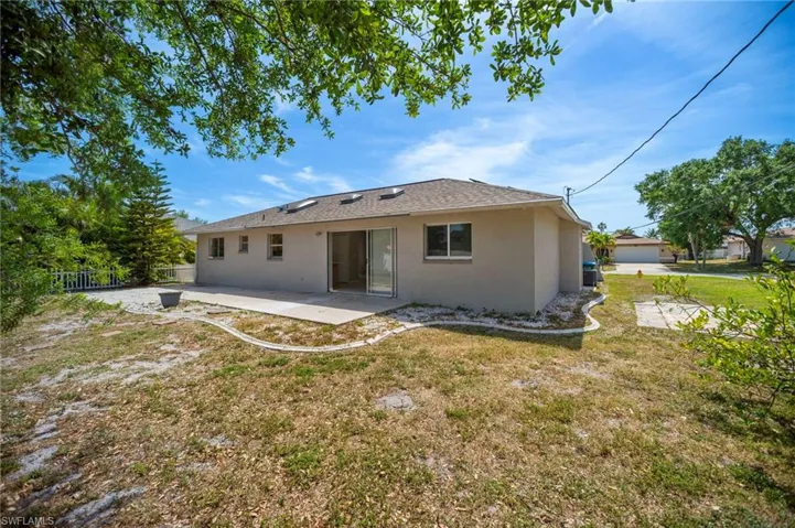 Rear view of house featuring stucco siding, fence, a yard, and a patio area