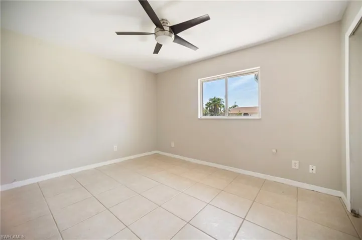 bedroom #1 with light tile patterned floors, baseboards, and a ceiling fan