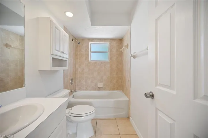 Bathroom featuring toilet, tile patterned flooring, tub / shower combination, baseboards, and vanity