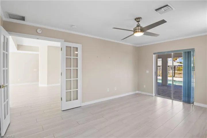 Primary suite with French doors opening to the pool and serene canal views—perfect for indoor-outdoor living.