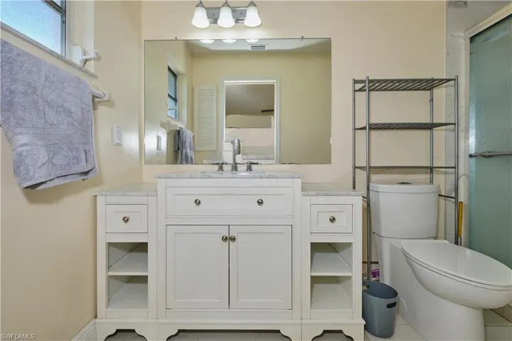 Bathroom featuring vanity with extensive cabinet space, tile flooring, and toilet