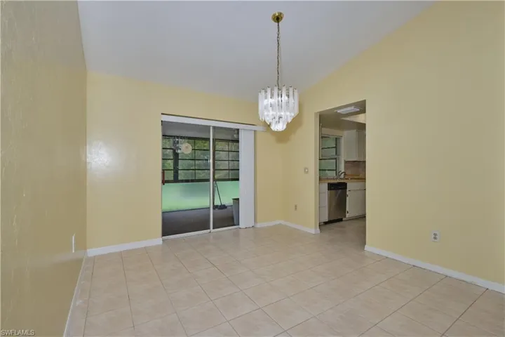 Tiled empty room featuring a chandelier and vaulted ceiling