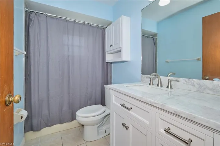 Bathroom featuring tile floors, vanity with extensive cabinet space, and toilet