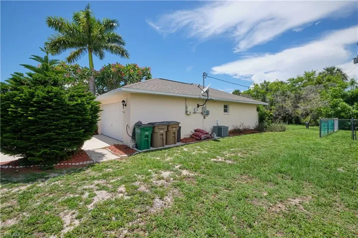 Rear view of property featuring a lawn and central AC