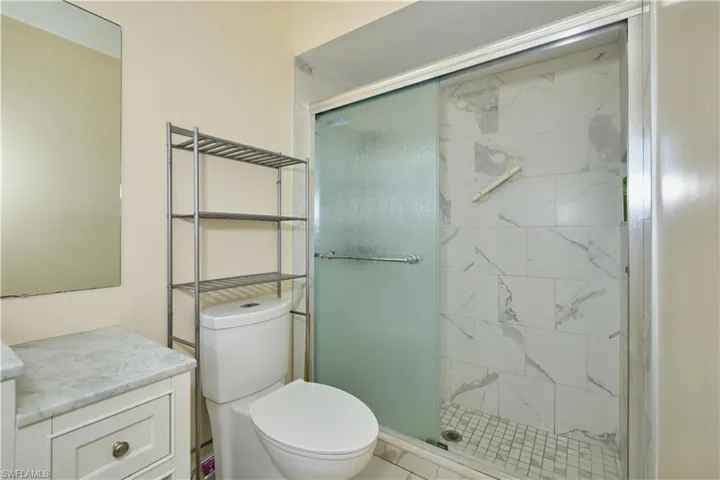 Bathroom featuring a shower with door, oversized vanity, and toilet
