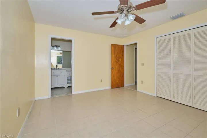 Unfurnished bedroom with a closet, light tile flooring, ensuite bathroom, ceiling fan, and sink