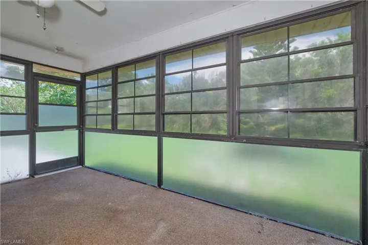 Unfurnished sunroom with plenty of natural light and ceiling fan