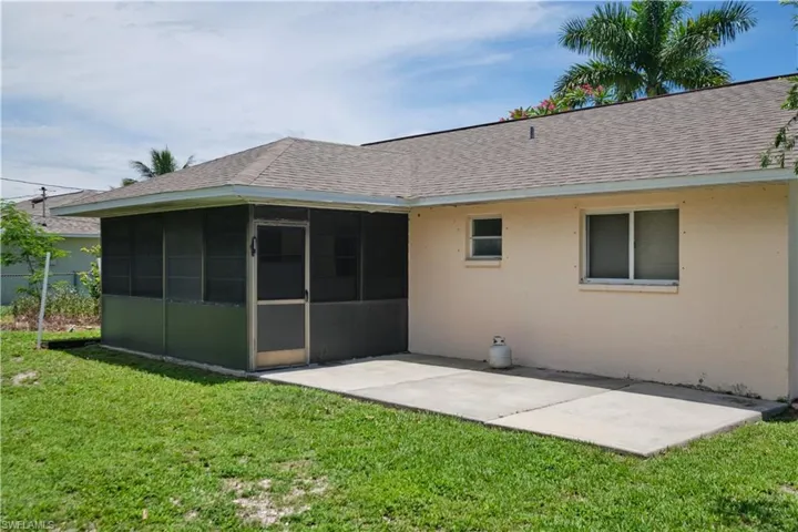 Rear view of house with a sunroom and a lawn
