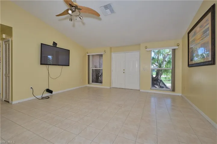 Unfurnished living room with vaulted ceiling, ceiling fan, and light tile floors