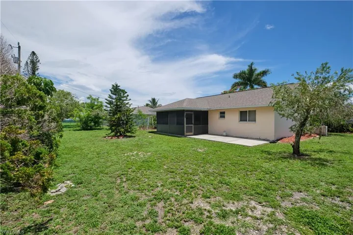 Rear view of property with a sunroom, a lawn, and a patio