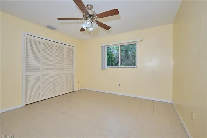 Unfurnished bedroom with ceiling fan, a closet, and light tile floors
