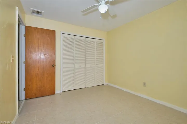 Unfurnished bedroom featuring ceiling fan, a closet, and light tile floors