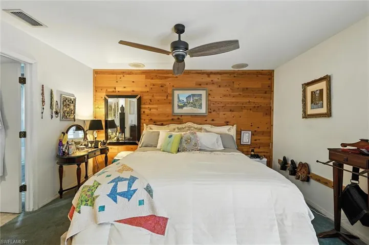 Carpeted bedroom featuring wood walls and ceiling fan