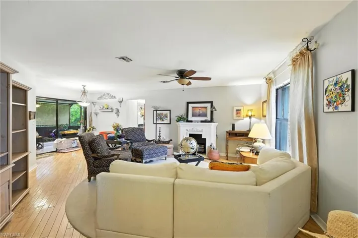 Living room with ceiling fan, light wood finished floors, and a fireplace