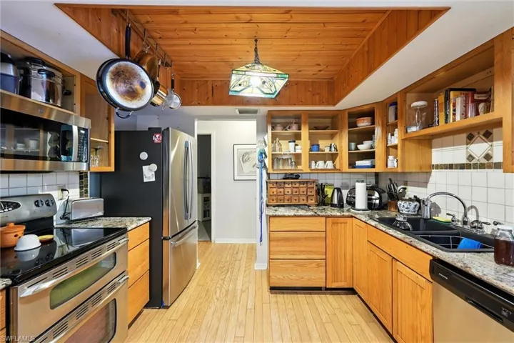 Kitchen featuring appliances with stainless steel finishes, open shelves, tasteful backsplash, and wooden ceiling