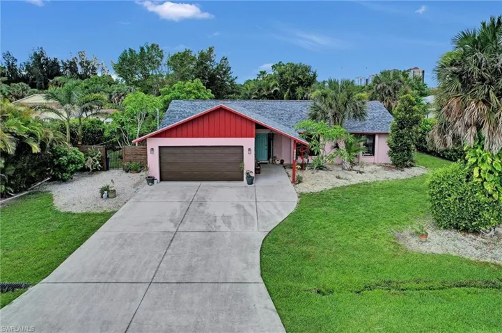 View of front of property with a garage, driveway, a front yard, and a shingled roof