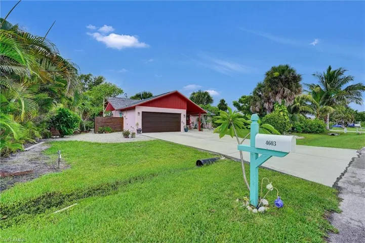 View of front of property with an attached garage, a front yard, and driveway