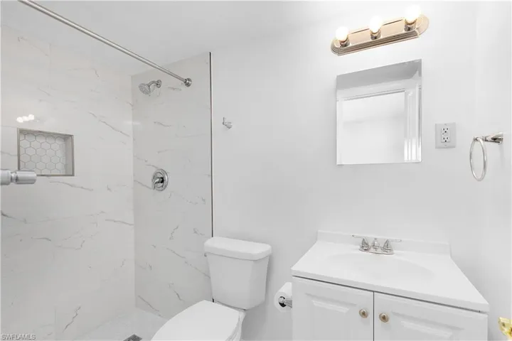 Bathroom with toilet, tiled shower, and vanity