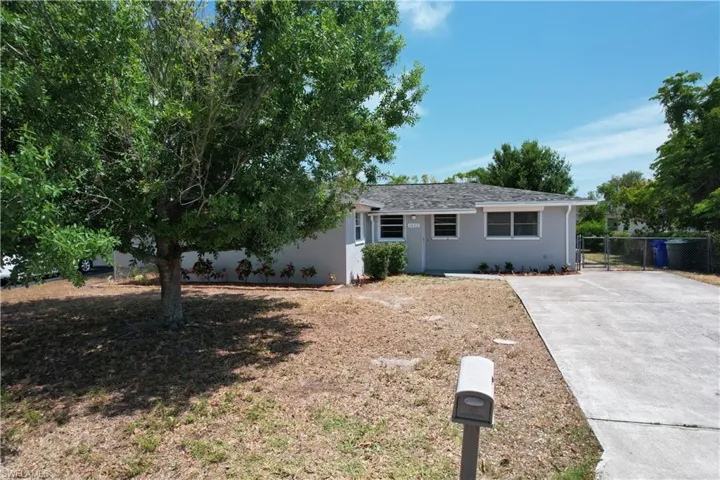 View of front of house with stucco siding, driveway, and fence