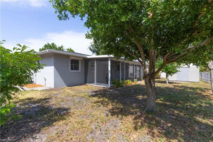 Rear view of property with a sunroom, stucco siding, an outdoor structure, and fence