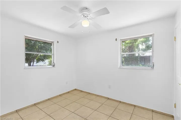 Empty room featuring ceiling fan, light tile patterned flooring, baseboards, and plenty of natural light