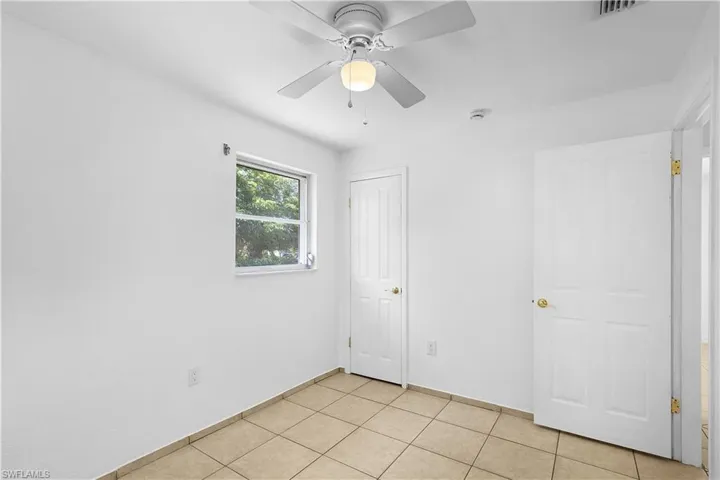 Unfurnished bedroom with a closet, light tile patterned floors, baseboards, ceiling fan, and visible vents
