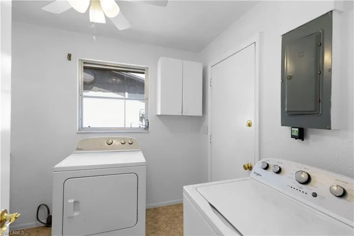 Clothes washing area with a ceiling fan, laundry area, electric panel, washer and clothes dryer, and baseboards