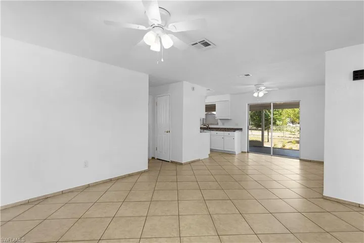 Unfurnished living room featuring visible vents, baseboards, and a ceiling fan