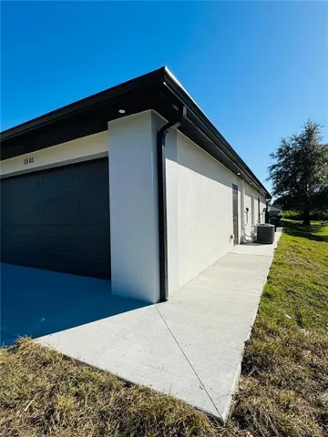 View of side of home featuring a lawn, cooling unit, and a garage