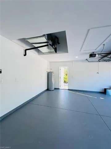 Garage featuring electric water heater and a garage door opener