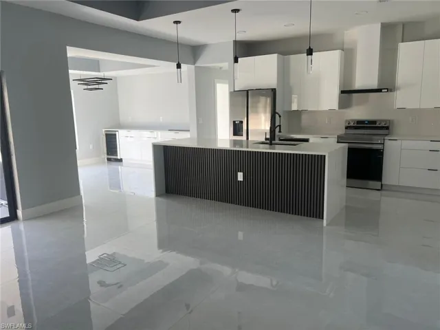 Kitchen featuring stainless steel appliances, an island with sink, modern cabinets, and white cabinetry